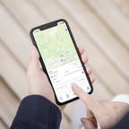 Person holding a smartphone with a map application on the screen.